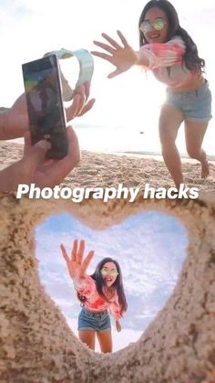 two girls are playing in the sand with their cell phones and one girl is making a heart shape