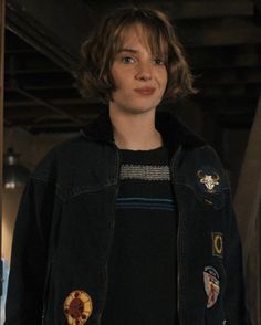 a young person wearing a black jacket with patches on it