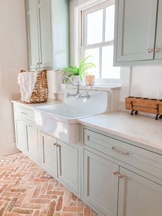 a white kitchen sink sitting under a window next to a counter with a basket on it