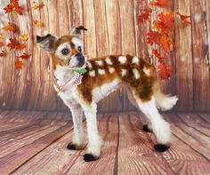 a small brown and white dog standing on top of a wooden floor next to leaves