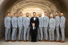 a group of men standing next to each other wearing suits and bow ties in front of a tunnel