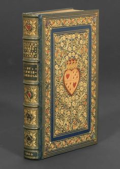 an old book with gold and blue trimmings on the front cover, featuring a heart