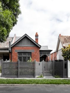 a house that has a fence in front of it and some bushes on the side