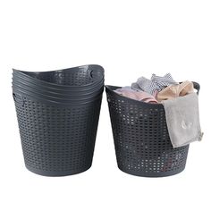 two black plastic baskets with clothes in them on a white background, side by side