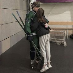 a man and woman standing next to each other in front of a wall with skis on it