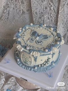 a blue and white cake sitting on top of a table next to a lace doily