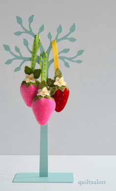 two strawberries with flowers and ribbons on top of each other in the shape of a tree