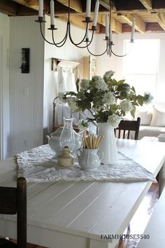 a white table topped with vases filled with flowers next to a chandelier