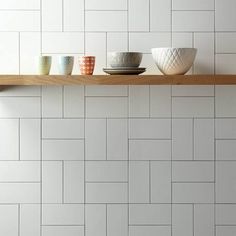 three bowls are sitting on a shelf in front of a white tile backsplash