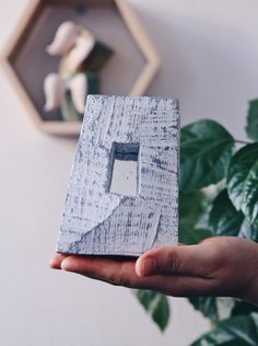 a person holding up a piece of wood with a hole in the middle and white paint on it