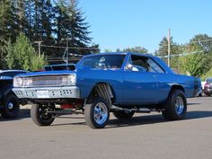 a blue car parked in a parking lot next to other cars on the side of the road