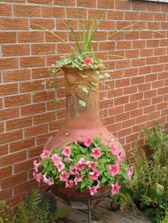 a vase with pink flowers in it sitting on top of a planter next to a brick wall