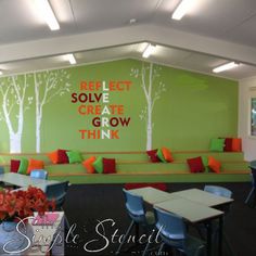 an empty cafeteria with green walls and red pillows on the bench seats, and trees painted on the wall