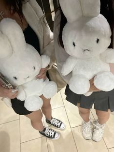 two women holding stuffed animals in their hands while standing next to each other on the floor