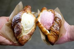 two croissants with powdered sugar and ice cream on them are being held by someone