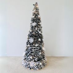 a black and white christmas tree with snowflakes on it's top, in a room