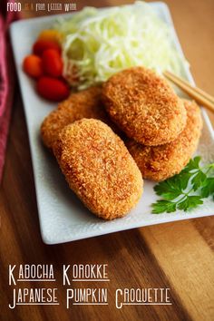 some fried food on a white plate with chopsticks and tomatoes in the background