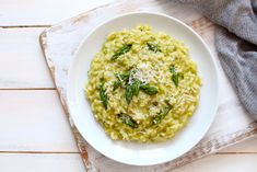 a white plate topped with pasta covered in parmesan cheese and spinach leaves