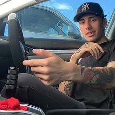 a man sitting in the driver's seat of a car with tattoos on his arm