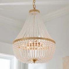 a chandelier hanging from the ceiling in a room with white walls and windows