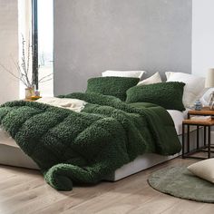 a bed covered in green fluffy blankets and pillows