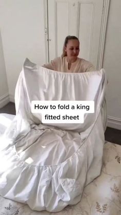 a woman sitting on top of a bed covered in white sheets with the words how to fold a fitted sheet