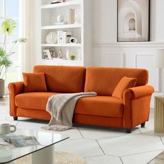 an orange couch in a living room with white walls and floor tiles on the floor