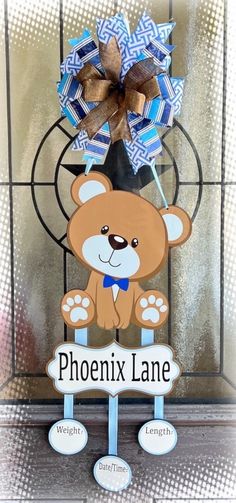 a wooden sign with a teddy bear holding a blue bow on it's head