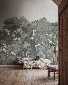 a room with a bed, chair and wallpaper on the walls that has trees painted on it