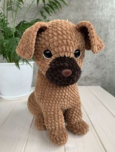 a stuffed dog sitting on top of a wooden table next to a potted plant