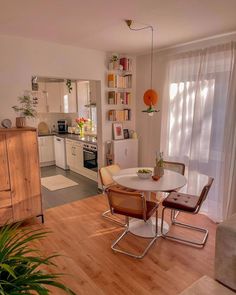 a kitchen and dining room with wood flooring, white walls and wooden furniture in it