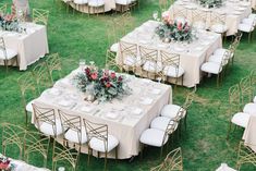 tables and chairs are set up in the grass for an outdoor wedding reception with floral centerpieces