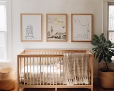 a baby crib in the corner of a room with three pictures on the wall