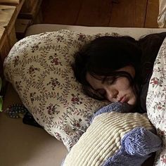 a woman laying in bed with her head on the pillow and covering herself from cold weather