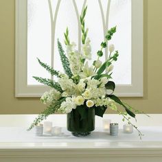 a vase filled with white flowers sitting on top of a table next to some candles