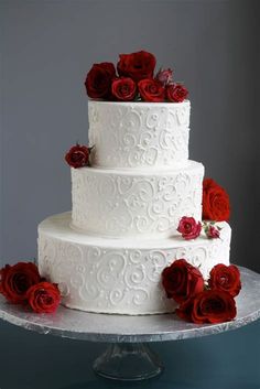 a three tiered white cake with red roses on top