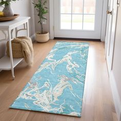 a blue and white rug on the floor in front of a door with a potted plant