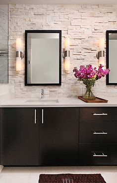 a bathroom with two sinks, mirrors and lights on the wall above them is shown