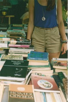 a woman standing in front of a table full of books