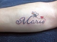 a tattoo with the word marie written in cursive font and a bee on it