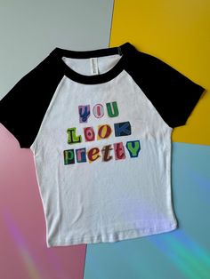 This is a SUPER CUTE and trendy cropped baby tee with black sleeves and a quote saying "you look pretty" in magazine cut out style.  Designs  are sublimated on a soft bella canvas shirt making it super high quality and comfy.  Washing: Machine was cold inside out to prevent fading!  *this is a one of one item only one is available currently in a size extra small. all items are handmade!  *if you are looking for a different size or color please feel free to reach out for custom orders (subject to an additional charge)*  *if you have any comments, suggestions, or concerns please do not hesitate to reach out Pink Baby Tee, Black Sleeves, Shirt Making, Rose T Shirt, Trendy Graphic Tees, Baby T Shirts, Pink Baby, Baseball T Shirts, Graphic Tees Women