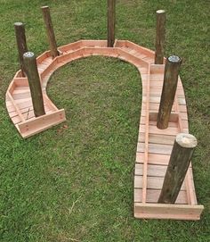 a small wooden bridge made out of wood sticks and logs in the grass with two poles sticking out of it