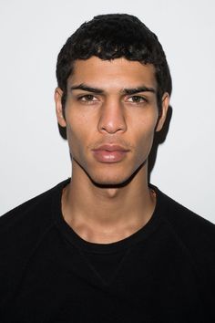 a close up of a person wearing a black shirt and looking at the camera with a serious look on his face