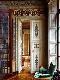 a room with many bookshelves and a chair in front of an open door