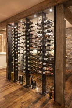 a wine cellar filled with lots of bottles and glasses on the wall next to a wooden floor