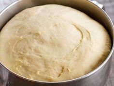 a metal pan filled with dough on top of a wooden table