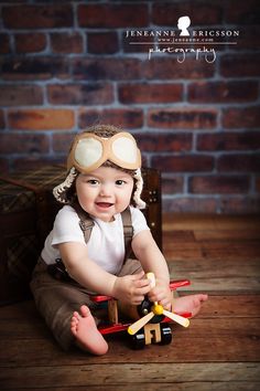 a baby is sitting on the floor playing with toy planes and smiling at the camera