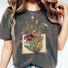 This Book and Flowers Shirt is a perfect gift for any Bookish, Book Lover or Literary fans who adore Light Academia Clothing. This  floral shirt has a vintage aesthetic so you will love the look of this cute tee. Gildan is back with its garment-dyed t-shirt, a fully customizable tee made 100% with ring-spun cotton. The soft-washed, garment-dyed fabric brings extra coziness to your wardrobe while the relaxed fit makes it an excellent daily choice. The double-needle stitching throughout the tee ma Spring Bookish Style Short Sleeve T-shirt, Books With Flowers, Bookish Short Sleeve T-shirt For Spring, Spring Bookish T-shirt With Letter Print, Spring Bookish Short Sleeve T-shirt, Spring Botanical T-shirt With Floral Design, Spring Cottagecore Printed T-shirt, Librarian Gifts, Academia Clothing