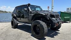 a black jeep parked next to the water