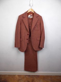 Vintage late 1970's men's three piece suit in reddish brown herringbone tweed fabric. Suit includes jacket, vest, and pants. Pants have zipper fly and flared pant legs. All pieces are lined and in very good vintage condition with no stains or damage. Freshly dry cleaned.  Label: Chess King, made in Yugoslavia Jacket tagged size 38*; actual measurements are 27" long, 16" shoulders, 24" shoulders, 36" chest Vest tagged size 38"; actual measurements 36" chest, 32" waist Pants tagged size 30*; actual measurements 30" waist, 12" rise, 34" inseam *Please note that vintage clothing and contemporary sizes can vary greatly. We take measurements of listed garments by laying the garment flat and then doubling the measurement. When considering whether a garment would fit, we suggest taking a similar g Vintage Tweed Suit For Formal Occasions, Brown Three-piece Suit With Notch Lapel For Fall, Brown Wool Three-piece Single Breasted Suit, Brown Wool Single-breasted Three-piece Suit, Brown Single-breasted Wool Three-piece Suit, Brown Wool Three-piece Single-breasted Suit, Brown Wool Three-piece Suit For Winter, Brown Fitted Three-piece Suit For Fall, Fitted Brown Three-piece Suit For Fall